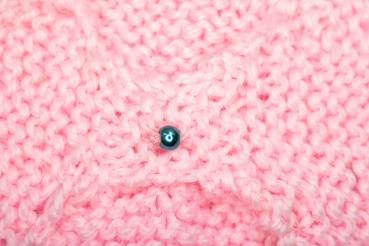 Hand knitted brooch in pink with blue pearl